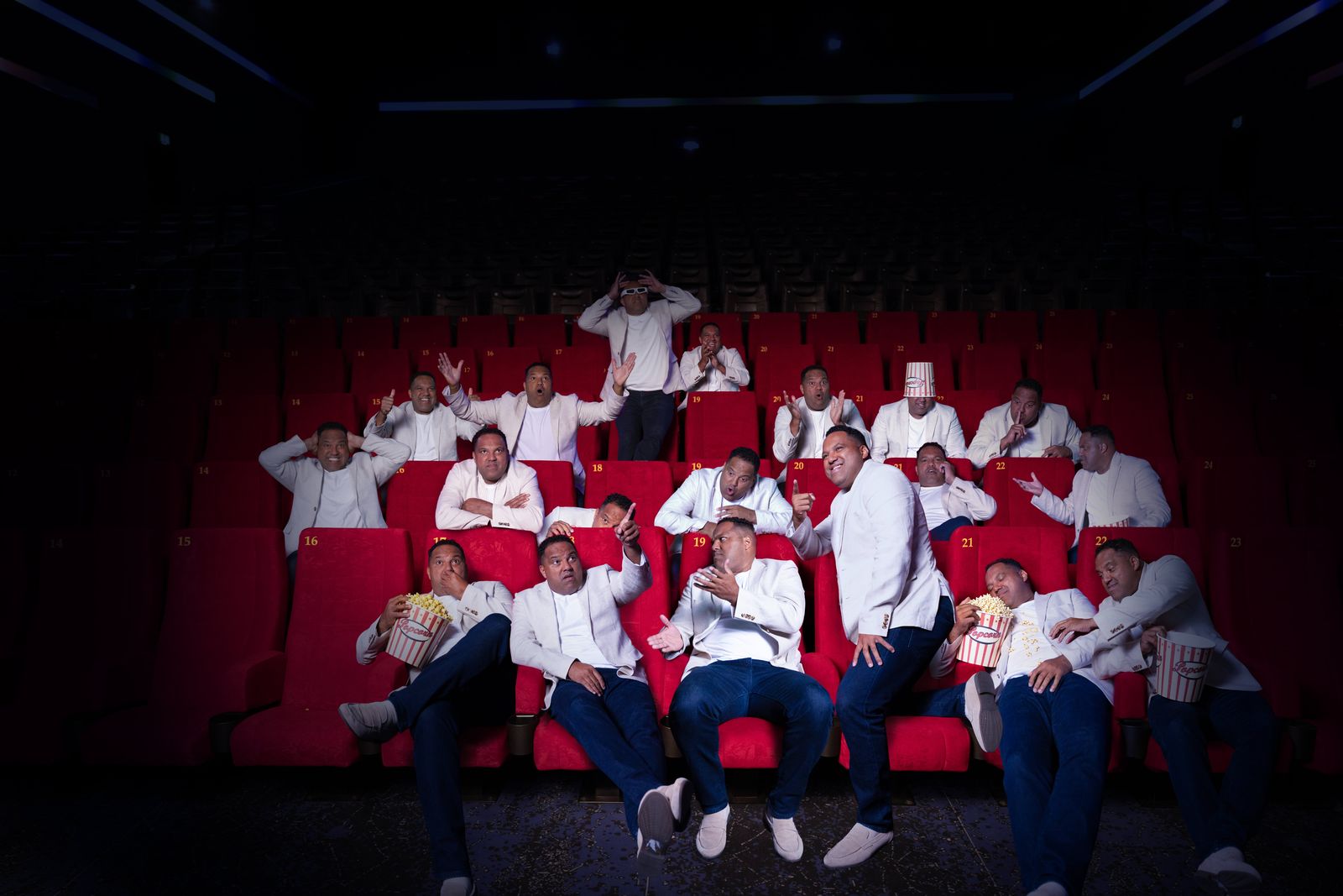 Ein ganzer Kinosaal voller Ailtons im weißen Sakko – mit Popcorn, 3D-Brille und Popcorn-Eimer auf dem Kopf