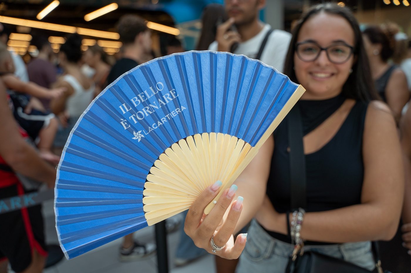 Besucherin mit Fächer „Il bello è tornare“ in der Warteschlange
